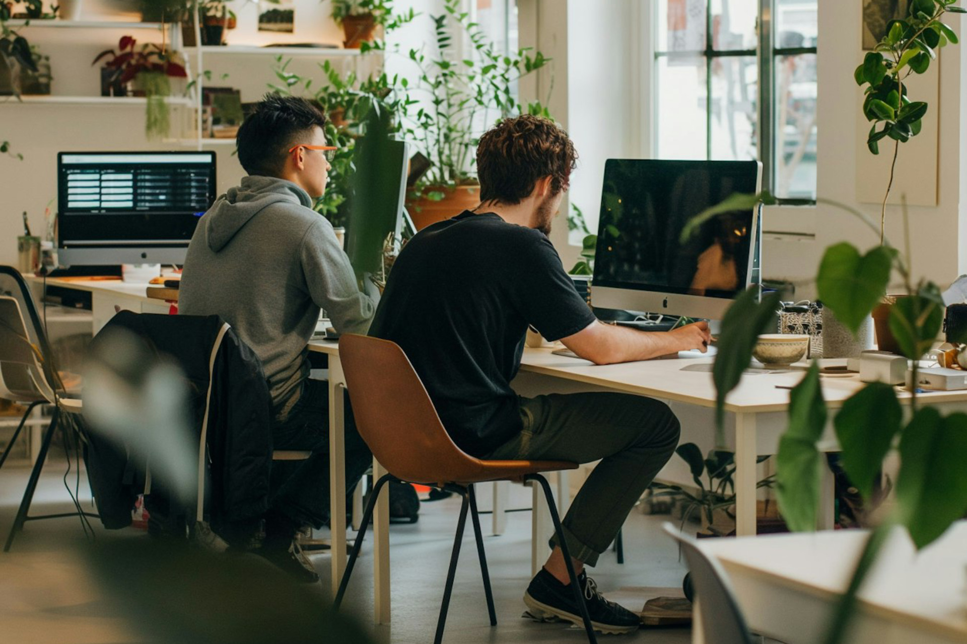 Työntekijöitä modernissa toimistossa, jossa paljon viherkasveja.