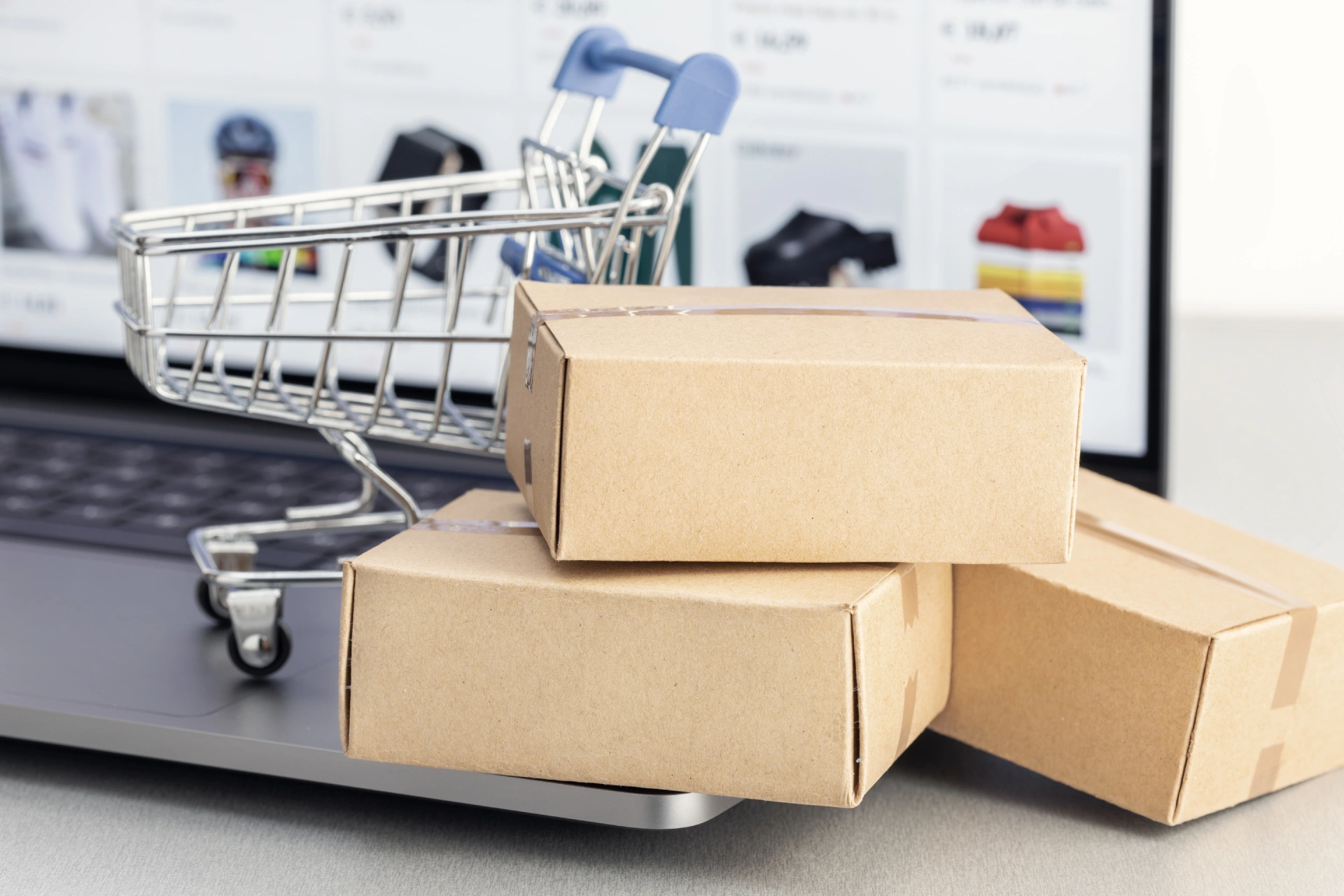 Verkkokauppa kannattavan tietokoneen näytöllä ja sen edessä pienet ostoskärryt ja paketteja.